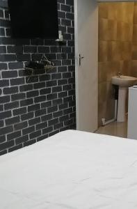 a bedroom with a white bed and a brick wall at Mels in Richards Bay