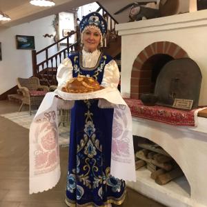 a woman holding a plate of food next to a fireplace at Gostevaya Izba Na Istre in Istra