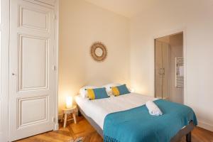 ein weißes Schlafzimmer mit einem Bett und einem Spiegel in der Unterkunft DIFY Le Belize - Bellecour in Lyon