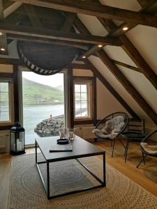 een woonkamer met een tafel en uitzicht op de oceaan bij Løðupakkhúsið - Historical Warehouse - Top Floor in Sørvágur