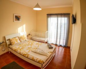 a bedroom with a bed with a crib and a window at O DRAGOEIRO da Madalena! in Porto Santo