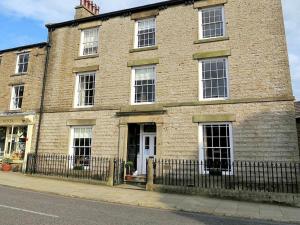 Skeldale House 'All Creatures Great & Small' by Maison Parfaite - Luxury Apartments & Studios in Askrigg, Yorkshire Dales في آسكريج: مبنى من الطوب امامه سياج