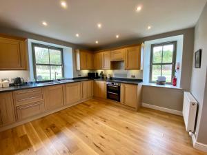 a large kitchen with wooden cabinets and wooden floors at Dunvegan Castle The Farmhouse Cottage in Dunvegan