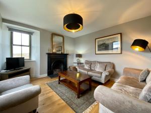 a living room with two couches and a fireplace at Dunvegan Castle The Farmhouse Cottage in Dunvegan