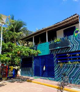 um edifício azul com plantas ao lado dele em Hostel Ave Rara na Praia do Francês