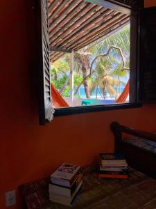 a window with a stack of books in a room at Hostel Ave Rara in Praia do Frances