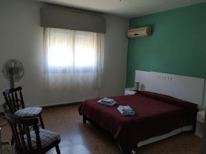 een slaapkamer met een bed, een stoel en een raam bij DOÑA OLGA in Minas