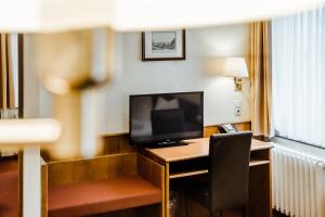 Habitación de hotel con escritorio y TV. en Hotel am Marschiertor en Aquisgrán