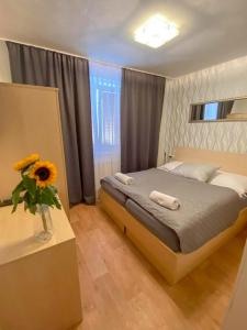Penzion Hustopeče في هستوبيس: غرفة نوم مع سرير و إناء من زهور الشمس على طاولة