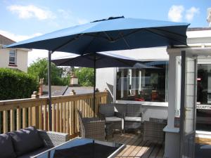 una sombrilla azul en una terraza con sillas y mesa en The Westgate, en Torquay