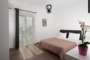 a white bedroom with a bed and a window at Aestas Apartments in Agia Marina Nea Kydonias