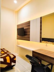 Cette chambre dispose d'un bureau, d'une télévision et d'une chaise. dans l'établissement La Tana Hotel, à Bagongsabrangan