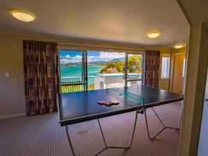 a ping pong table with a view of the water at Bay Breeze - Stephens Bay, Kaiteriteri Home in Kaiteriteri
