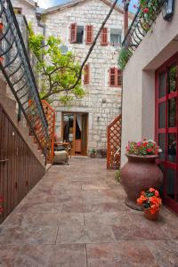 a courtyard with a stone building and a vase with flowers at Apartments Porat in Sveti Stefan