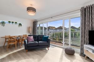 sala de estar con sofá, mesa y ventana en 25 Coedrath Park - Sea Views from Balcony, Short Walk to Beach, Parking, en Saundersfoot