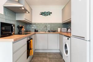 a kitchen with white cabinets and a washer and dryer at 25 Coedrath Park - Sea Views from Balcony, Short Walk to Beach, Parking in Saundersfoot
