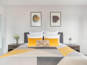 una camera da letto con un grande letto con cuscini gialli di numa I Oben Apartments a Francoforte sul Meno