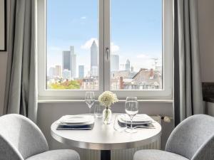 numa I Oben Apartments في فرانكفورت ماين: طاولة بيضاء مع كرسيين ونافذة