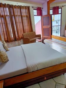 1 cama blanca grande en una habitación con ventanas en HOTEL HIMALYAN PARADISE, en McLeod Ganj