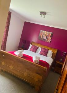 ein Schlafzimmer mit einem großen Holzbett mit lila Wänden in der Unterkunft Remus B&B in Lochgelly
