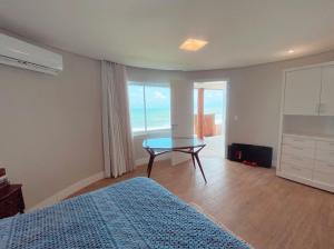a bedroom with a bed and a table with a view of the ocean at Luxo e pé na areia in Parnamirim +20 photos