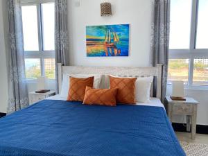 a blue bed with pillows in a bedroom with windows at Nyali Emirates Reef Apartment in Mombasa