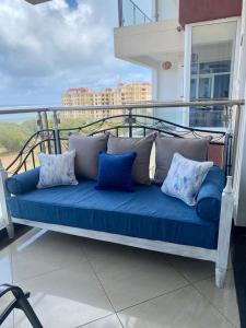 Sofá azul sentado en un balcón con almohadas en Nyali Emirates Reef Apartment, en Mombasa