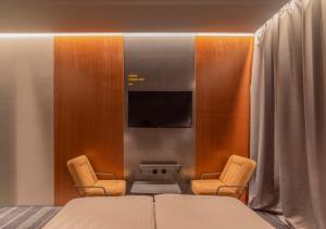 een slaapkamer met een bed en twee stoelen en een televisie bij Дизайн-готель ROAD in Kiev