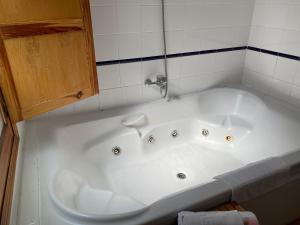 baño con bañera blanca y armario de madera. en Hostal Moscatel, en Málaga