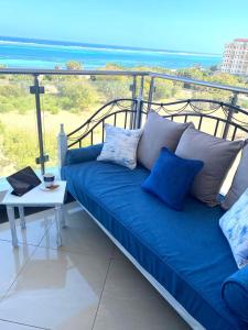 un sofá azul en un balcón con vistas al océano en Nyali Emirates Reef Apartment, en Mombasa