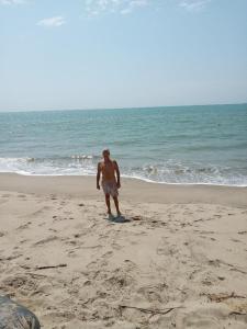 un hombre parado en una playa cerca del océano en LA CABAÑA DE HUERTAMAR en Zorritos