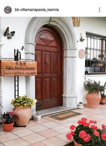 een houten deur in een gebouw met potplanten bij B&B Villa Maria Paola - Alloggi Temporanei Isernia in Isernia