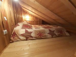 Ce lit se trouve dans une chambre mansardée en bois dotée d'un couvre-lit. dans l'établissement Appartement balcon Vue lac, à Gérardmer