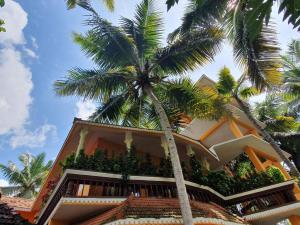 a building with palm trees in front of it at Thriphala Ayurveda Yogashram in Trivandrum