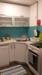a kitchen with white cabinets and a sink and a stove at Apartman sa garažom i internetom in Sarajevo