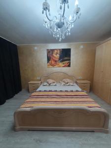 ein Schlafzimmer mit einem großen Bett mit einem Kronleuchter in der Unterkunft Kriss Apartment Luxury in Târgu Jiu