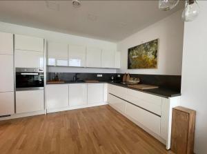 eine Küche mit weißen Schränken und einem Holzboden in der Unterkunft Modernes Apartment mit wunderschonem Rheinblick in Urmitz