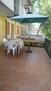 un patio con mesa, sillas y sombrilla en VACANZA A MIRAMARE en Rímini