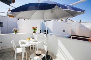 a white table with a blue umbrella on a balcony at Alojarte Mezquita 5 in Seville