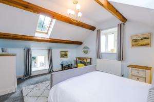 a bedroom with a white bed and two windows at Tan Y Bryn Ganol in Cwm