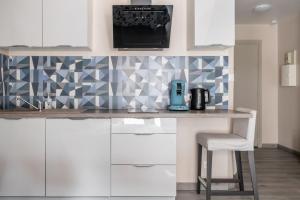 a kitchen with white cabinets and a counter with a chair at Studio centre historique, place de la réunion in Mulhouse