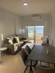 a living room with a couch and a table with chairs at Alex Beach Apartment 34 in Larnaca +39 photos