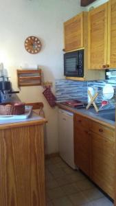 a kitchen with wooden cabinets and a counter top at Studio rénové jardin et vue - 1 chambre - 4 nuits minimum in Chaillol