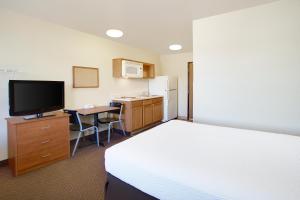 um quarto de hotel com uma cama, uma secretária e uma televisão em WoodSpring Suites Richmond Colonial Heights Fort Gregg-Adams em Colonial Heights