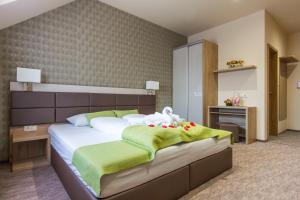 sypialnia z dużym łóżkiem z zieloną i białą pościelą w obiekcie Veres Motel w mieście Veresegyház