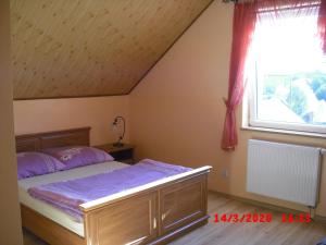 a bedroom with a bed with purple sheets and a window at Pokoje Gościnne HANA in Radków