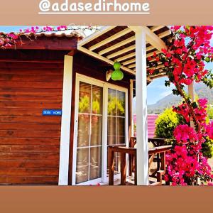 a porch of a house with a window and flowers at Ada Pansiyon Karaöz in Adrasan