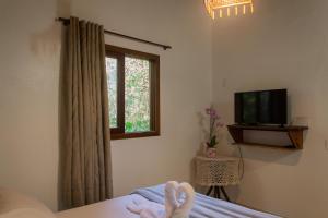 a bedroom with a bed and a tv and a window at Morada do Gabriel in Guarda do Embaú