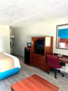 a hotel room with a bed and a desk and a television at Rodeway Inn in Lake Wales