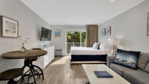 East Hampton House Resort في إيست هامبتون: غرفه فندقيه بسرير وطاولة واريكه